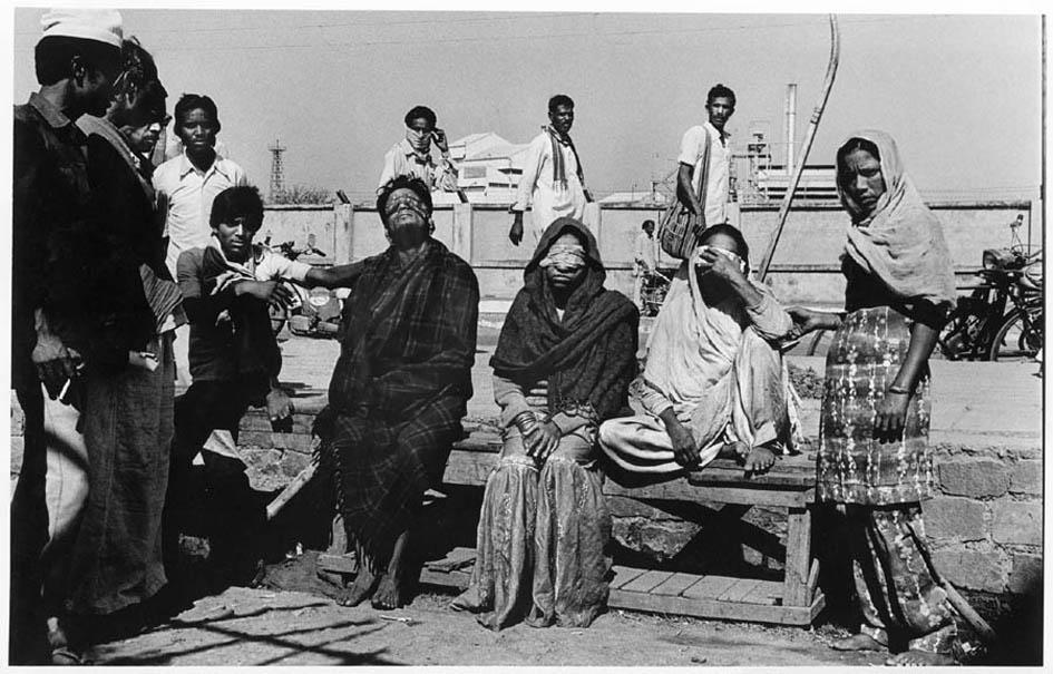 The morning after the Bhopal gas disaster people sit with covered eyes 