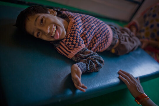 BHOPAL, INDIA - NOVEMBER 27:  12 year old Suraj Raghuwanshi is comforted as he receives care at the Chingari Trust clinic on November 27, 2009 in Bhopal, India. Twenty-five years after an explosion causing a mass gas leak, in the Union Carbide factory in Bhopal, killed at least eight thousand people, toxic material from the biggest industrial disaster in history continues to affect Bhopalis. A new generation is growing up sick, disabled and struggling for justice. The effects of the disaster on the health of generations to come, both through genetics, transferred from gas victims to their children and through the ongoing severe contamination, caused by the Union Carbide factory, has only started to develop visible forms recently.  Annan suffers from cerebral palsy and receives vital rehabilitative support and care at the Chingari Trust Clinic.  (Photo by Daniel Berehulak/ Getty Images)